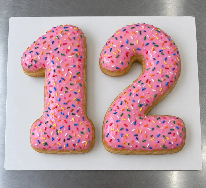 Two-number birthday cake: big donuts shaped like 1 and 2 with pink icing and sprinkles