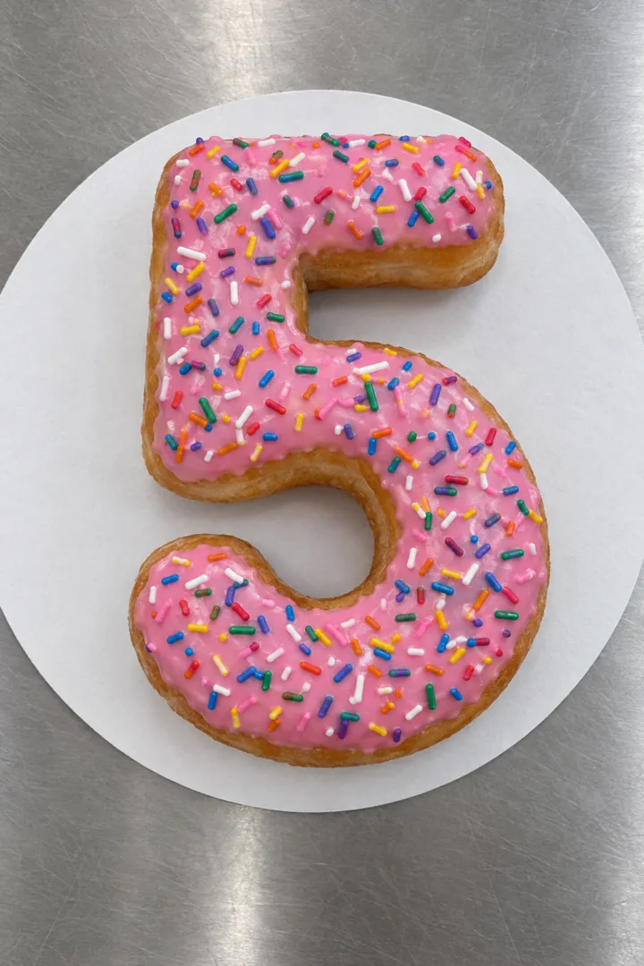 One-number birthday cake: a big donut shaped like a 5 with pink icing and sprinkles